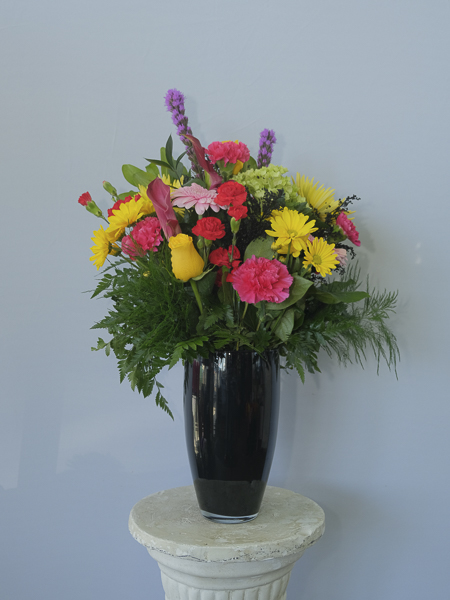 Black vase, yellow roses, pink and yellow flowers