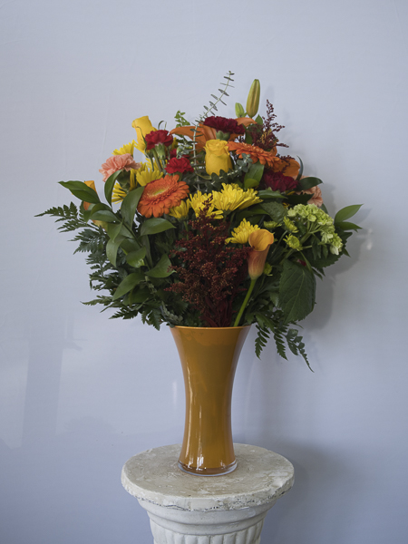 Mustard vase with yellow and orange flowers