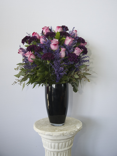 Pink Roses with purple carnations in a black vase